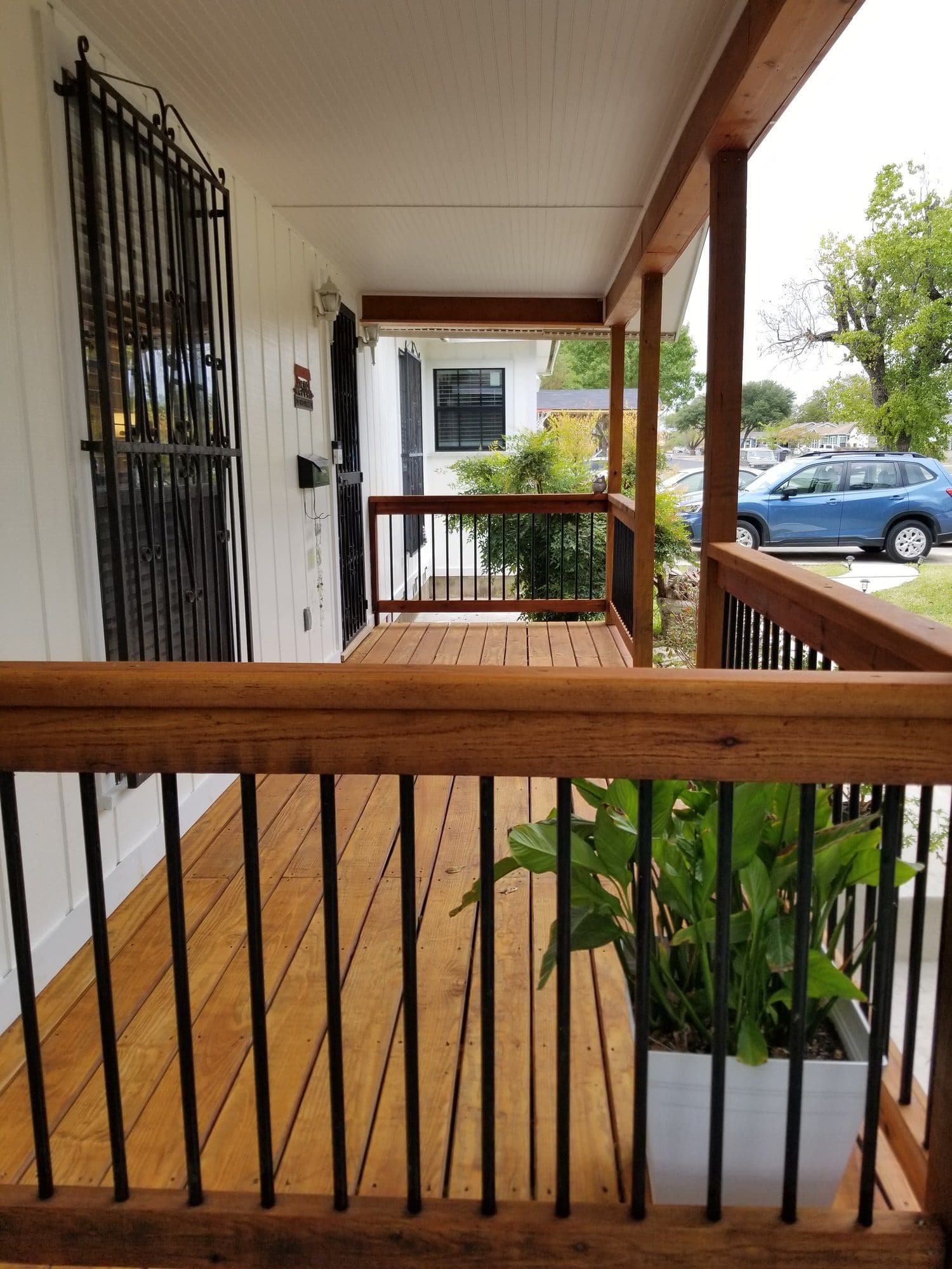 Covered porch with an exposed wood beam ceiling and wood railing