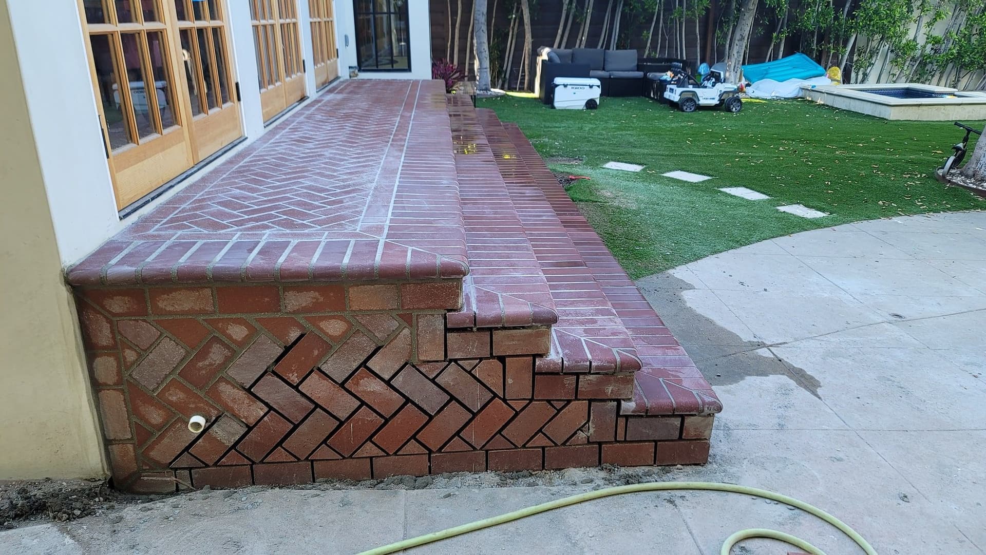 Brick paving and a stepped brick landing beside a lawn